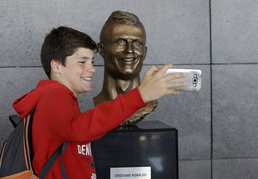 Ecco un ragazzino mentre scatta un selfie vicino al volto del suo idolo. Ap